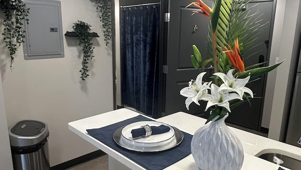 A hotel room with a small sitting area featuring a table, chairs, a vase with flowers, and a trash can. - Cozy and Clean 1 Bedroom Apt centrally located in Downtown Birmingham, Near UAB (Birmingham)