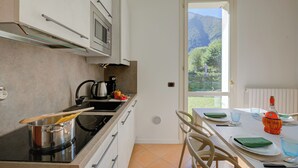 Una cocina moderna con estufa, ollas y vistas a la montaña a través de una ventana.
