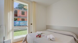 Una habitación de hotel con cama, ventana con cortinas y vistas a un edificio.
