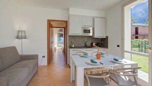 Una cocina moderna con armarios blancos, microondas y comedor con mesa y sillas.