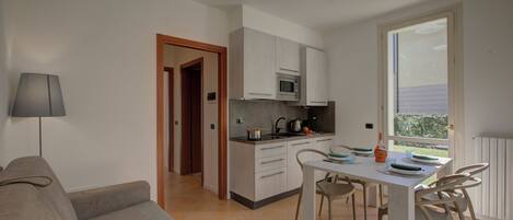 Un espacio habitable compacto con kitchenette, comedor y sofá.