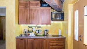 Una cocina pequeña con armarios de madera, un microondas y un lavamanos.