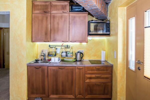 Una cocina pequeña con armarios de madera, un microondas y un lavamanos.