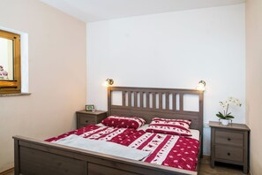 A neatly made bed with a patterned bedspread, a wooden headboard, and bedside tables with lamps. - Mt Krvavec Apartment Story (Cerklje na Gorenjskem)