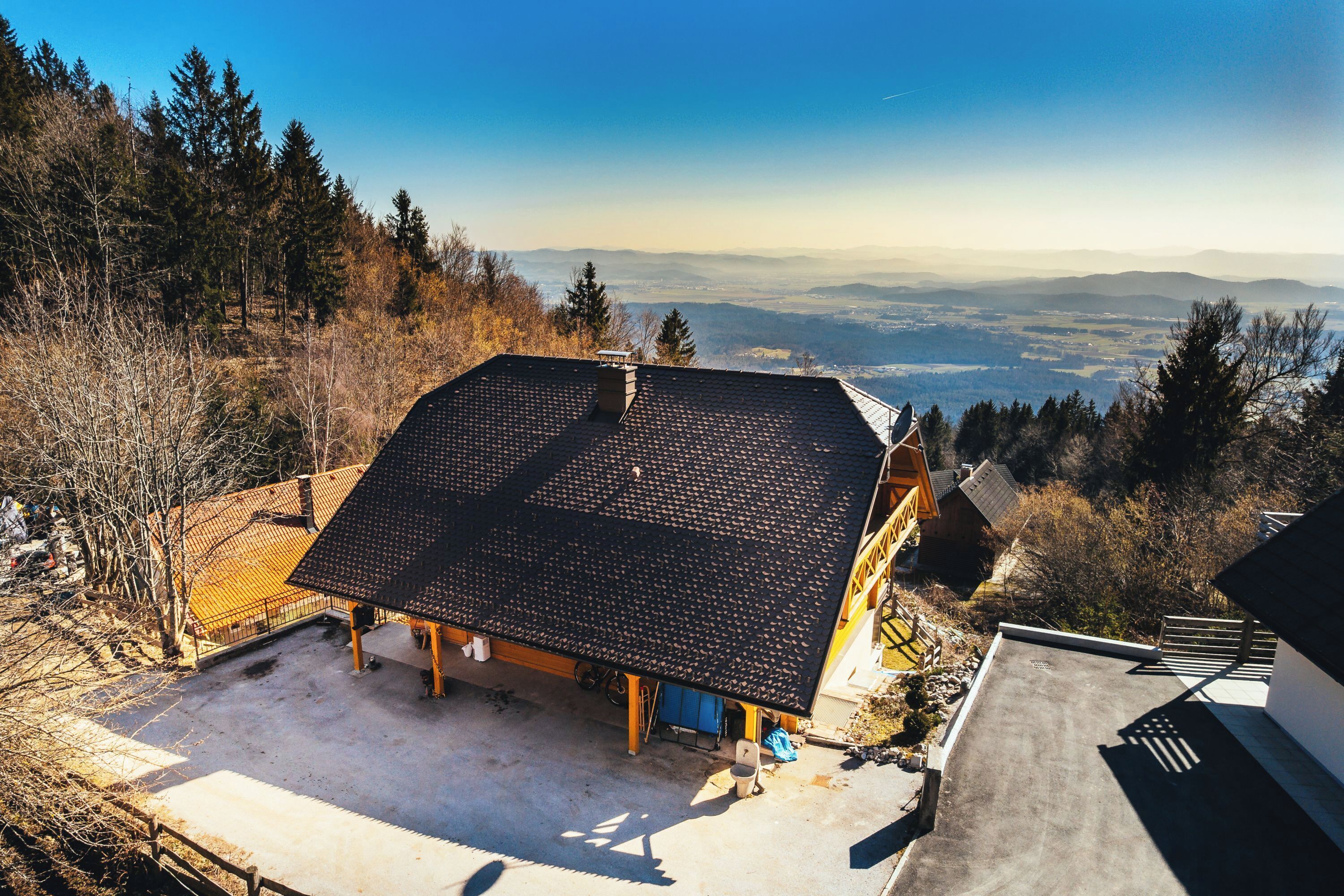Eine Chalet mit geneigtem Dach, umgeben von einer Holzterrasse und Blick auf ferne Berge.