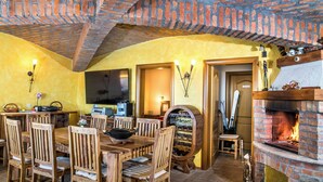 Un comedor con chimenea de ladrillo, mobiliario de madera y televisión.