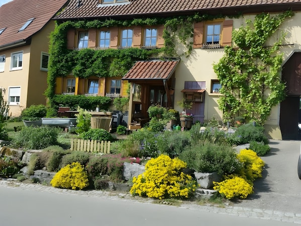 A two-story house with a garden in front, a wooden fence, and a paved driveway.
