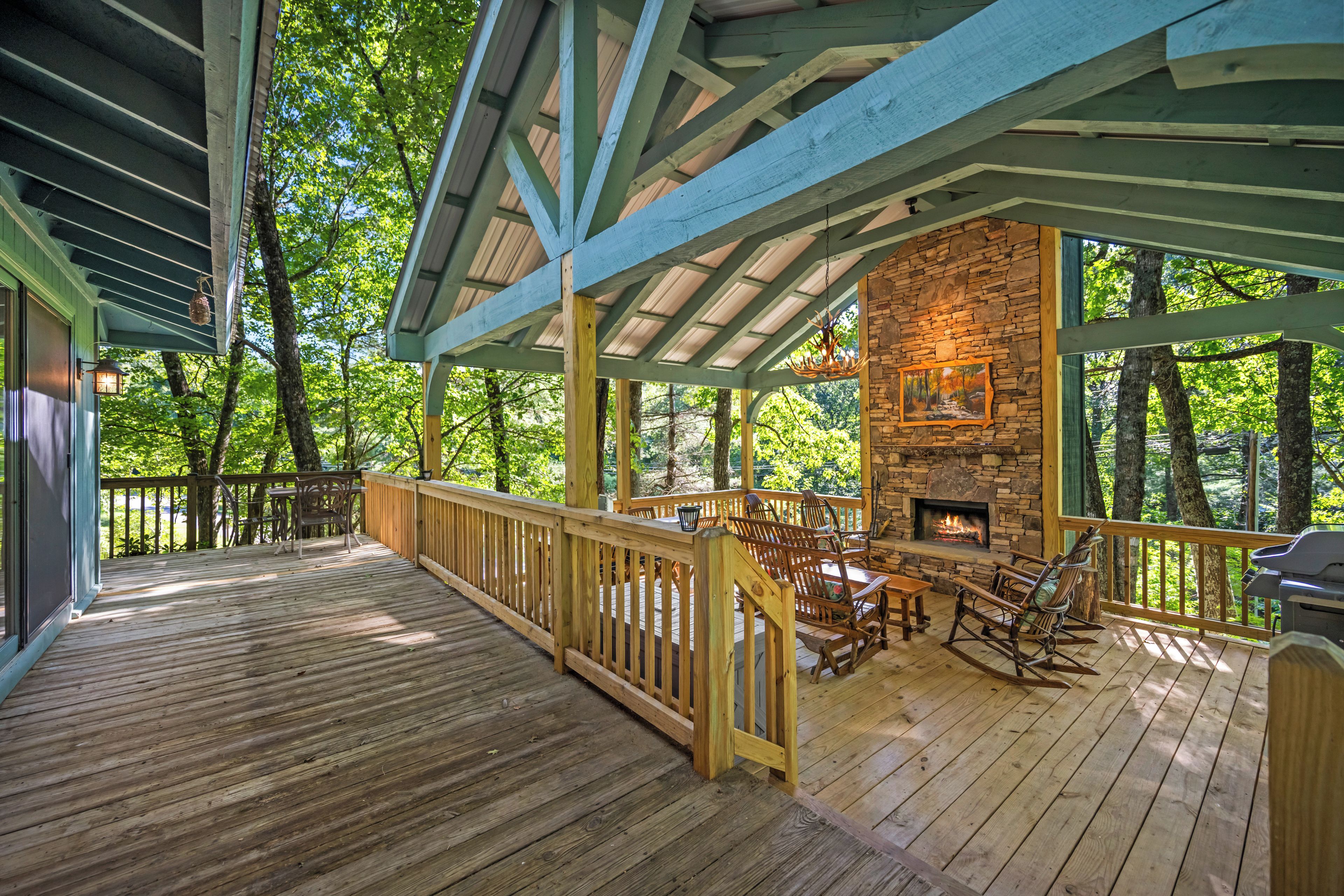 A wooden deck with a stone fireplace and outdoor seating.