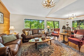 A spacious living room with leather sofas, a coffee table, and a chandelier.