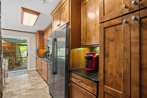 A kitchen with wooden cabinets, a stainless steel refrigerator, and a red coffee maker.