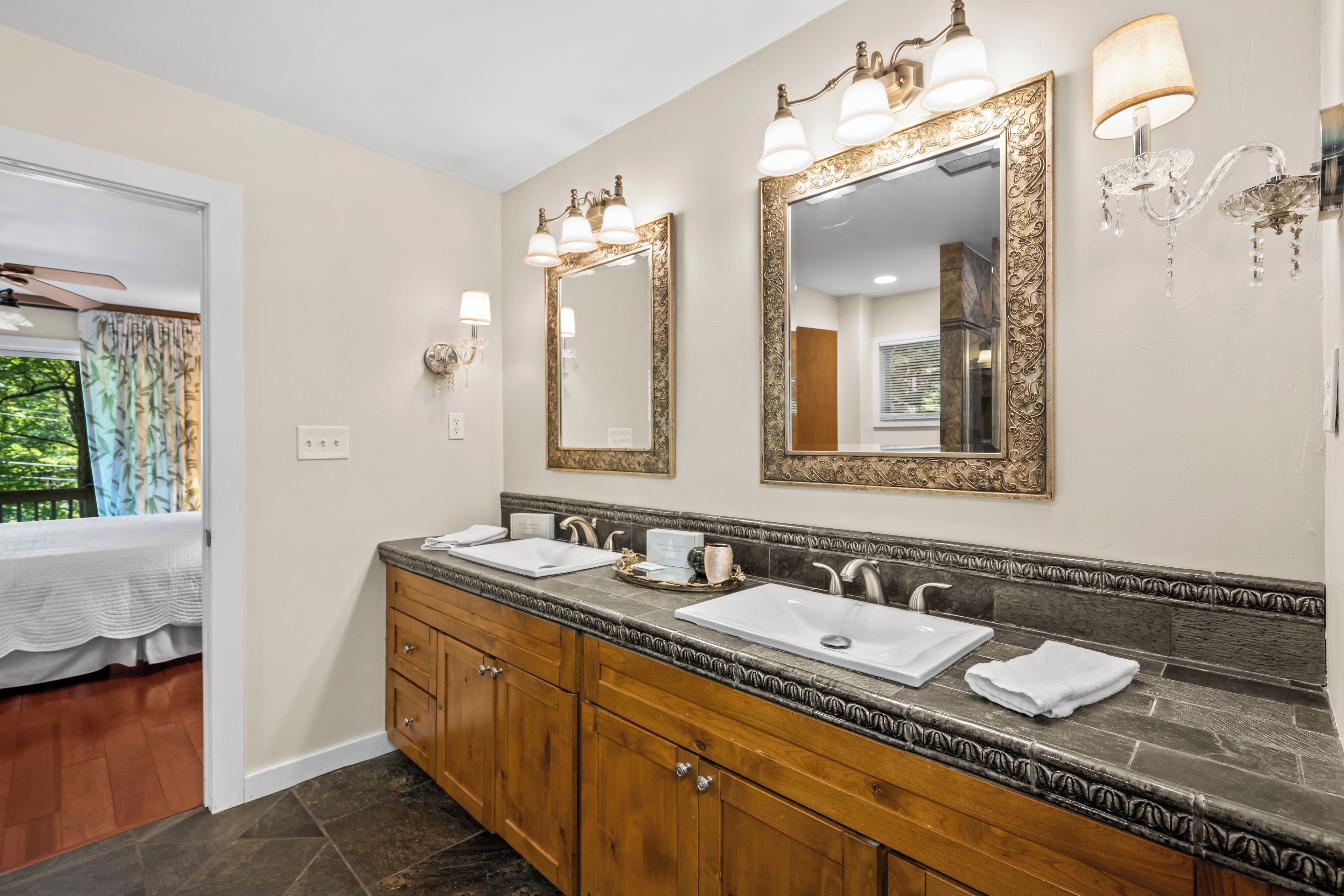 A bathroom with two sinks, wooden cabinets, and decorative wall sconces.