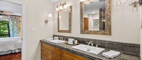 A bathroom with two sinks, wooden cabinets, and decorative wall sconces.