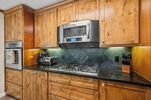 A kitchen with wooden cabinets, a stainless steel microwave, a gas stove, and a coffee maker.