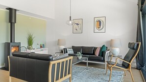 Een moderne woonkamer met een open haard, een bank, een salontafel, een fauteuil en twee wandlampen.