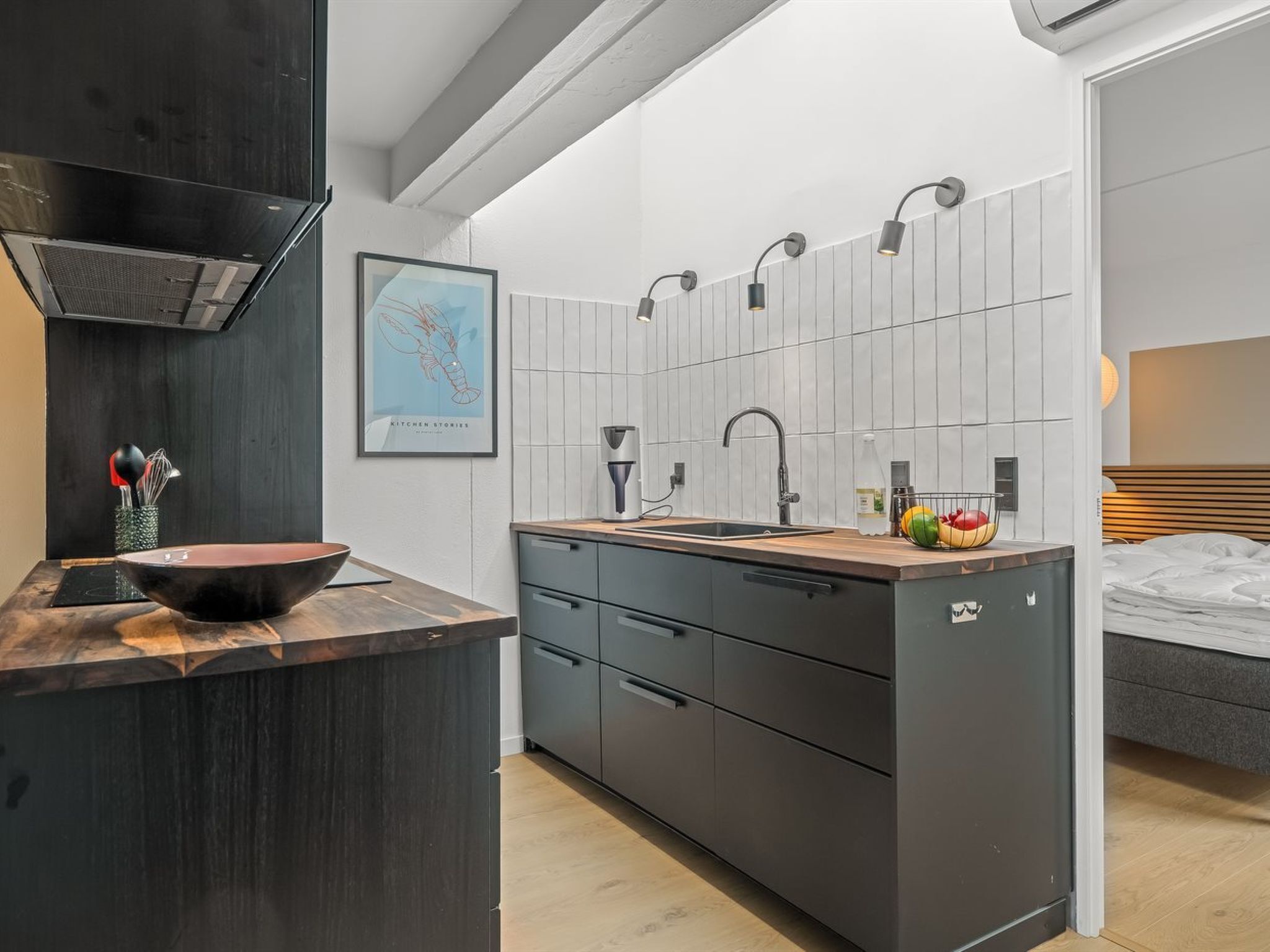 A modern kitchen with a wooden countertop, a black sink, and a backsplash.