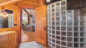 Un interior de madera con un amplio muro de vidrio y una puerta de madera, además de un área de baño visible con un lavamanos y espejo.