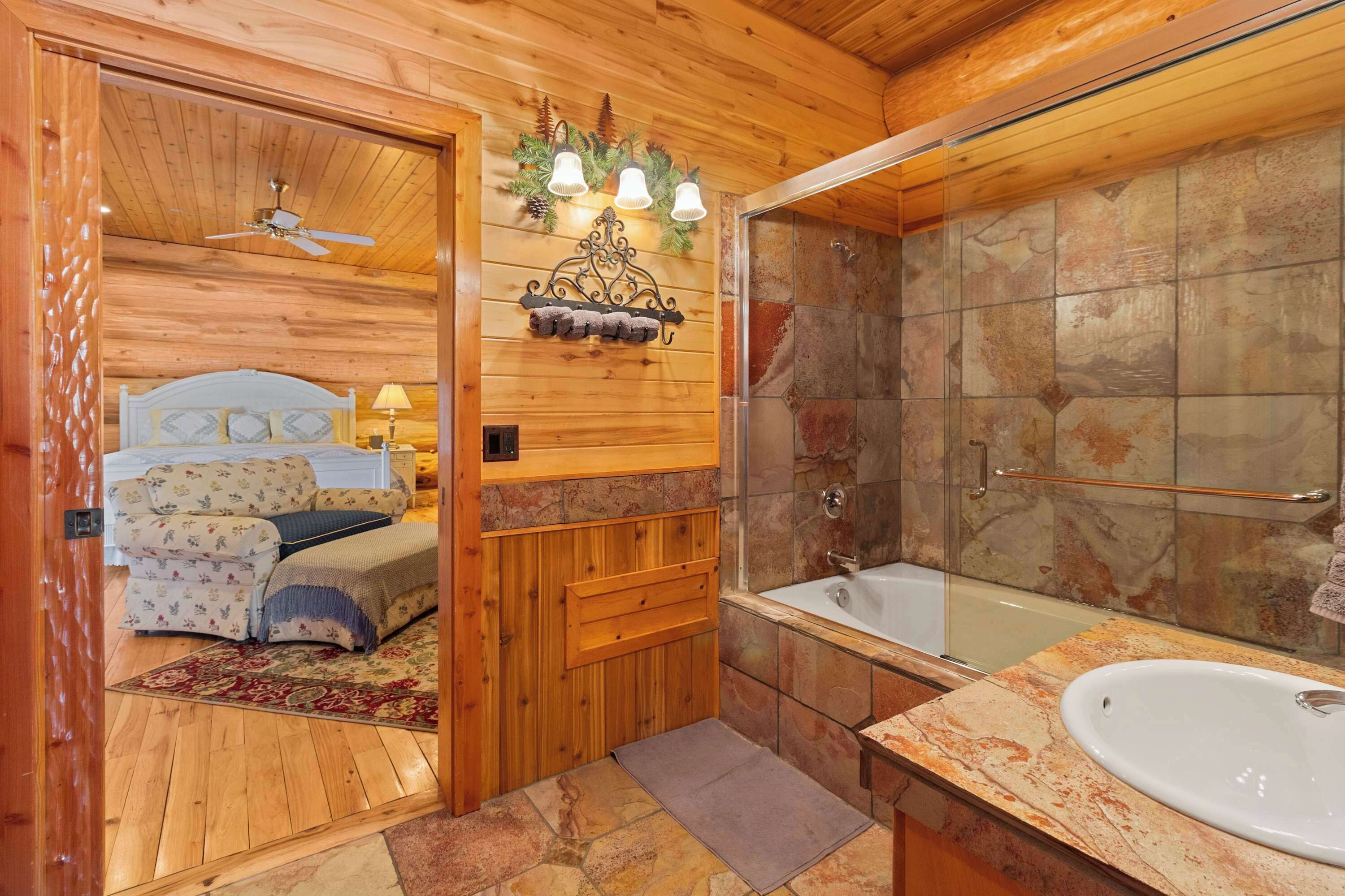 Een houten cabinemeubilair met een slaapkamer, een badkamer met een stenen douche en een groot bad.