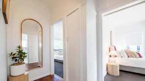 A hotel room with a wooden floor, a bed with white bedding, a bedside table with a lamp, and a large mirror on the wall. - The Palmer Cove - Stylish, Central (Dubbo)