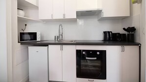 A modern kitchen with white cabinets, a black countertop, a microwave, a sink, and a built-in oven.