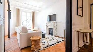 Ein modernes Wohnzimmer mit einem weißen Sofa, einem Kamin und einem an der Wand befestigten Fernseher.