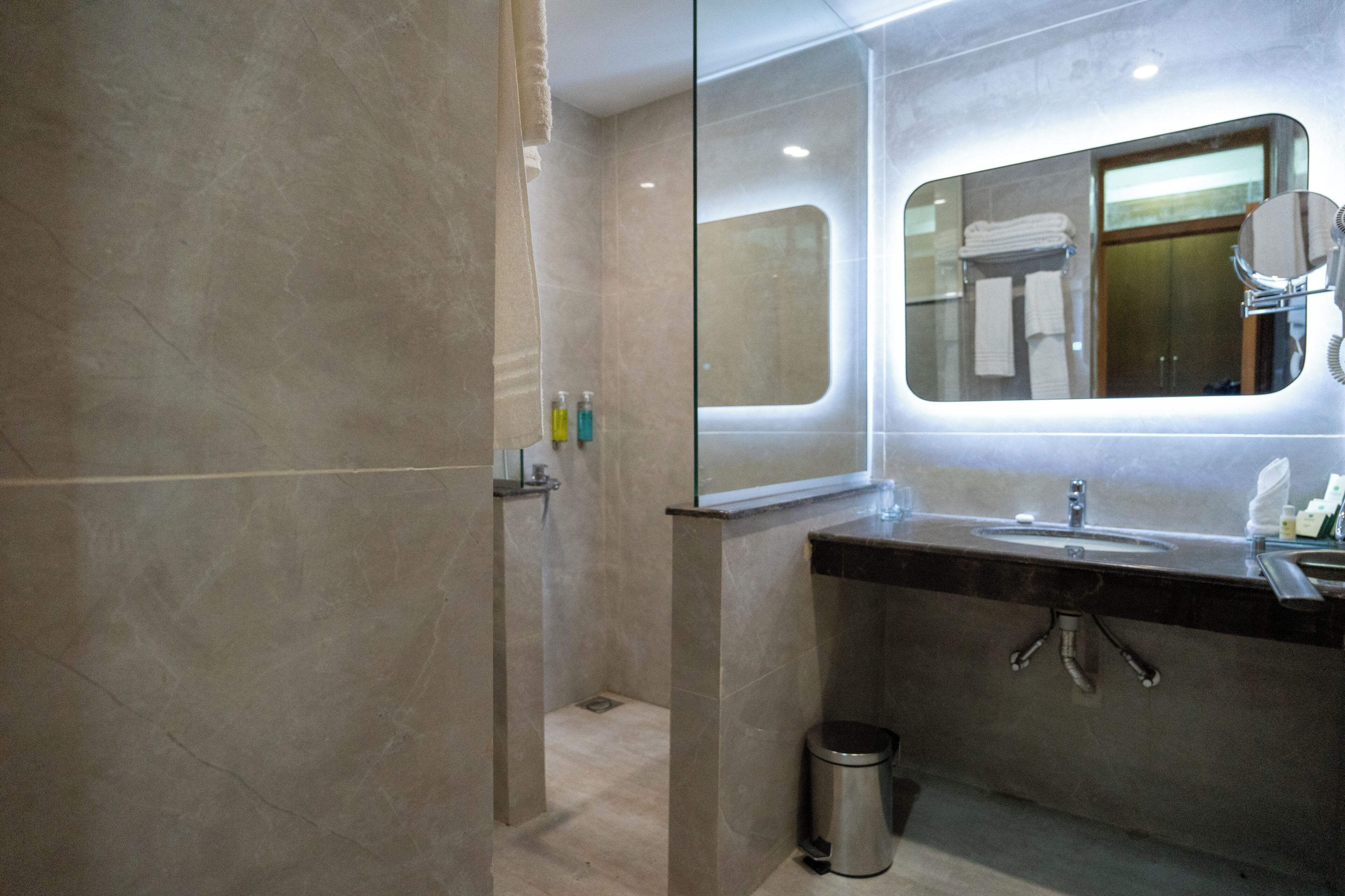 A modern bathroom with a glass-enclosed shower, a large mirror, and a sink with a vanity.