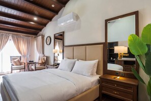 A hotel room with a large bed, a nightstand with a lamp, a mirror, and a wooden ceiling. - Green Pak Hotel Hunza (Karimabad)