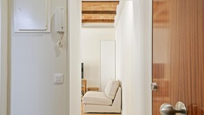 A modern interior with a wooden door, a white wall, and a beige sofa in the background. - Winahost La Barceloneta (Barcelona)