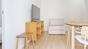 A modern, minimalistic living room with a flat-screen TV, wooden furniture, and a light-colored sofa. - Winahost La Barceloneta (Barcelona)