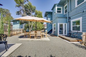 A patio area with a table and chairs, a wooden fence, and a blue building in the background. - Sip, Shop & Explore: San Diego Apartment (San Diego)