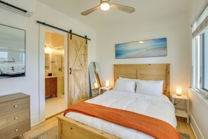A bedroom with a bed, a nightstand, a wall-mounted painting, a ceiling fan, and a sliding barn door. - Sip, Shop & Explore: San Diego Apartment (San Diego)
