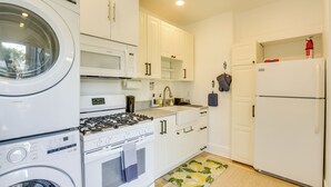 A compact kitchen with a washing machine, microwave, stove, sink, and refrigerator. - Sip, Shop & Explore: San Diego Apartment (San Diego)