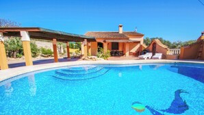 A swimming pool with a tiled deck, a covered patio area, and a small building with a tiled roof. - Finca Pineda - private pool villa in Benissa (Benissa)