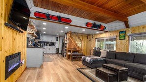 A cozy cabin interior with a wooden interior, a kitchen, a dining area, and a living room with a sofa and ottoman. - Tee & Ski Cabin | Mt Rainier, White Pass (Packwood)