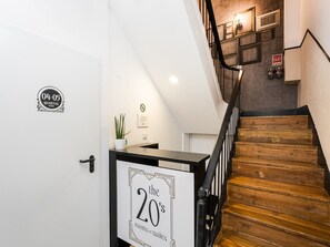 A staircase with wooden steps and black railings, a white door with a sign indicating '04-05 Quartos rooms,' and a sign on the wall advertising 'the 20's rooms & suites.' - The Twenties by GuestReady - Room 35 (Lisbon)