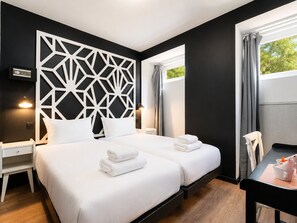 Une chambre d’hôtel avec deux lits, un bureau et une chaise.