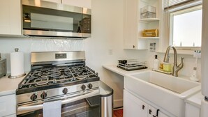Una cocina moderna con electrodomésticos de acero inoxidable, microondas integrado y pileta blanca.