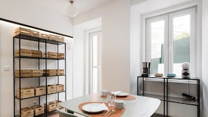 Una cocina moderna con una mesa de comedor preparada para dos personas, una cafetera y un ventanal con vistas al exterior.