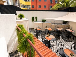 Une terrasse sur le toit avec des sièges en plein air, un coin cuisine et des plantes en pot.
