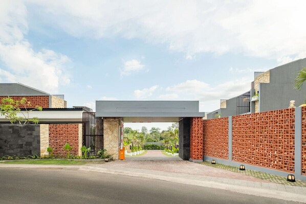 A modern building entrance with a covered walkway, stone and brick walls, and a clear sky.
