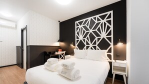 Ein modernes Hotelzimmer mit einem großen Bett, zwei Nachttischen, einem Schreibtisch und einer dekorativen Wandverkleidung.