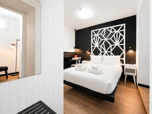 Une chambre d’hôtel moderne équipée d’un lit, de tables de chevet, d’un bureau et d’un panneau décoratif mural.