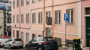 A pink building with multiple windows and a parking sign.