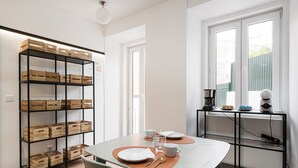 A modern kitchen with a dining table set for two, a coffee machine, and a window with a view of the outside.