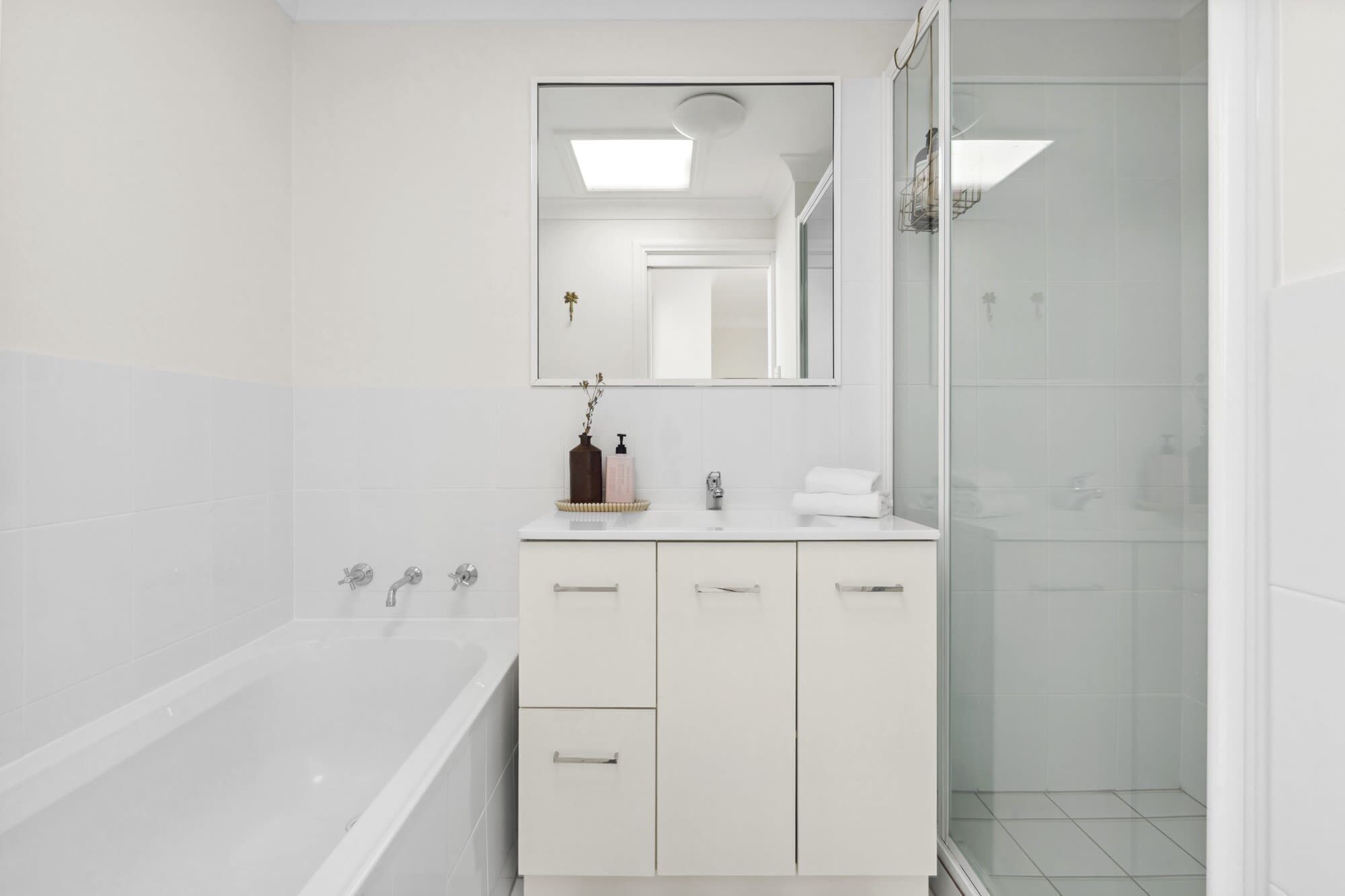 A modern bathroom with a bathtub, a vanity with a mirror, and a shower area.