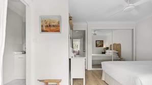 Un dormitorio con cama, escritorio, armario y un cuadro en la pared.