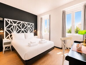 Een hotelkamer met een bed, nachtkastjes, een bureau en een stoel.