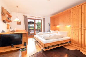 A bedroom with a bed, wooden wardrobe, TV, and a window with curtains. - Heustub'n Vacation Apartment (Reit im Winkl)