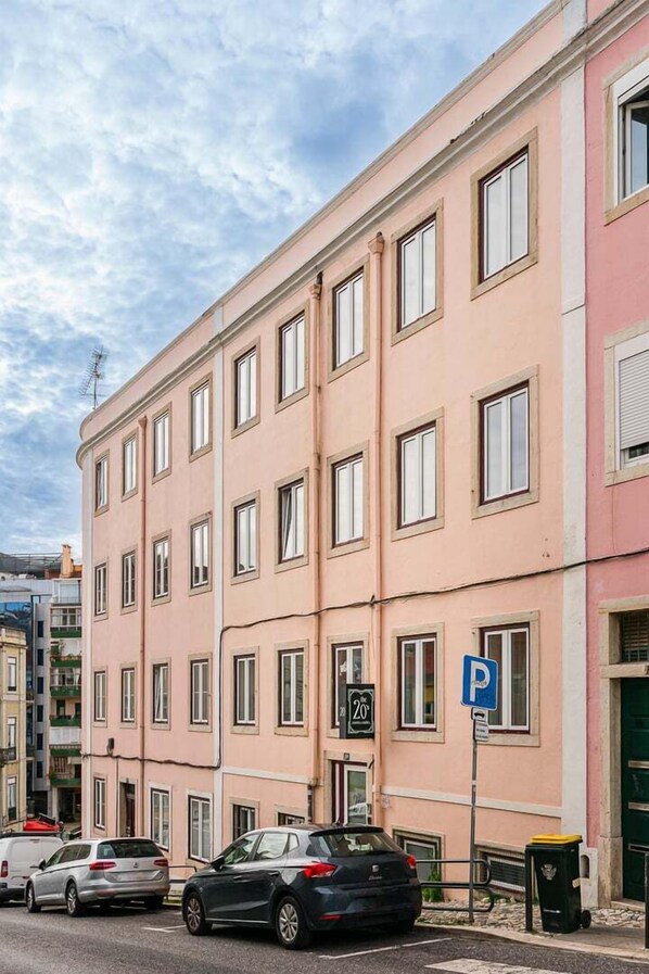 Un edificio rosa con varias ventanas y una señal de estacionamiento.