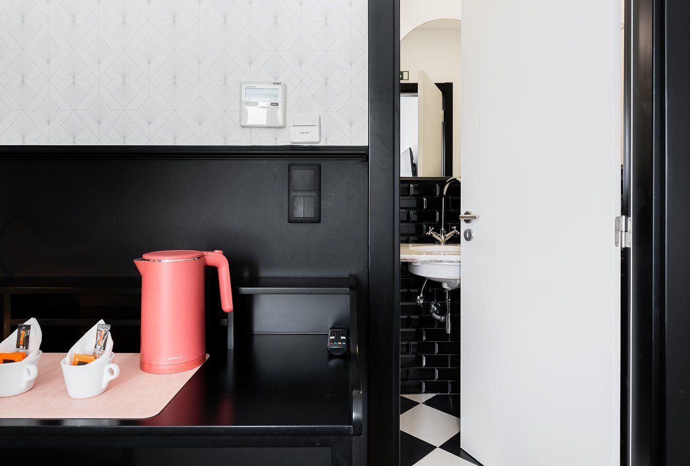 Een moderne keuken met een zwart aanrecht, een rode waterkoker en een koffieapparaat.