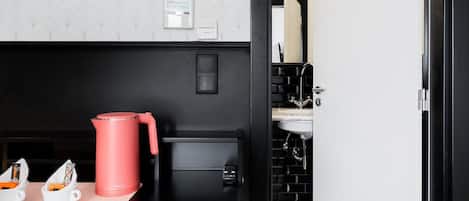 A modern kitchen with a black countertop, a red kettle, and a coffee machine.